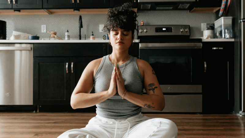 Woman sitting in a kitchen, practicing meditation and yoga