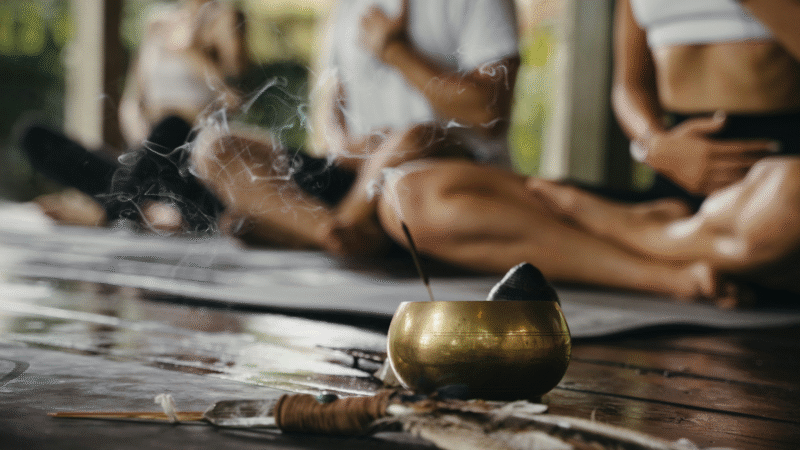 A group of people practicing breath meditation with an incense nearby